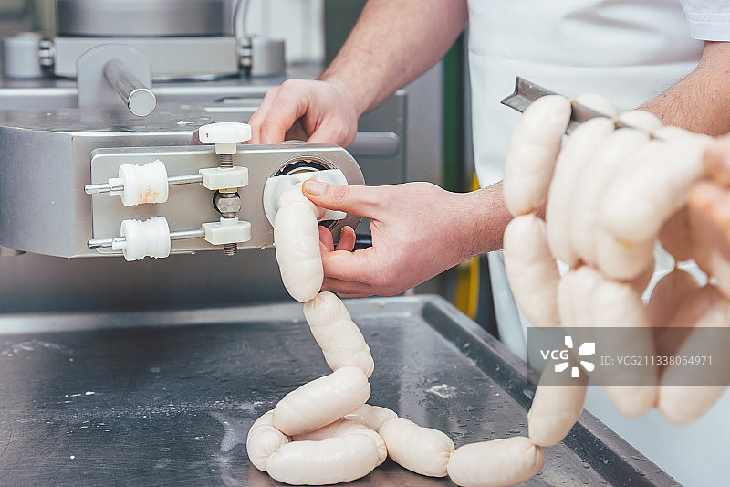 肉铺里的屠夫用链子给香肠填馅图片素材