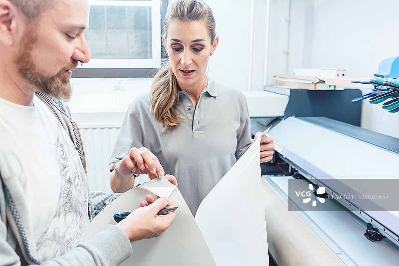 男人和女人讨论大版面印刷的技术细节图片素材