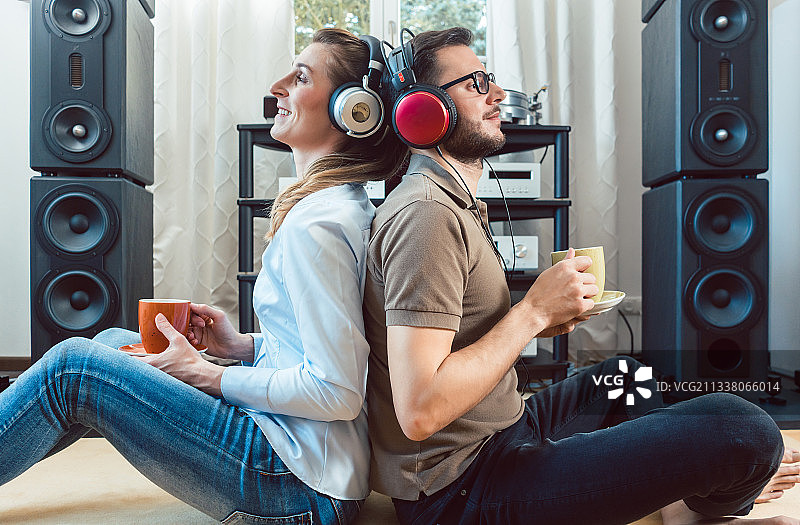 情侣们戴着耳机，互相倚靠着，欣赏着高保真立体声的音乐图片素材