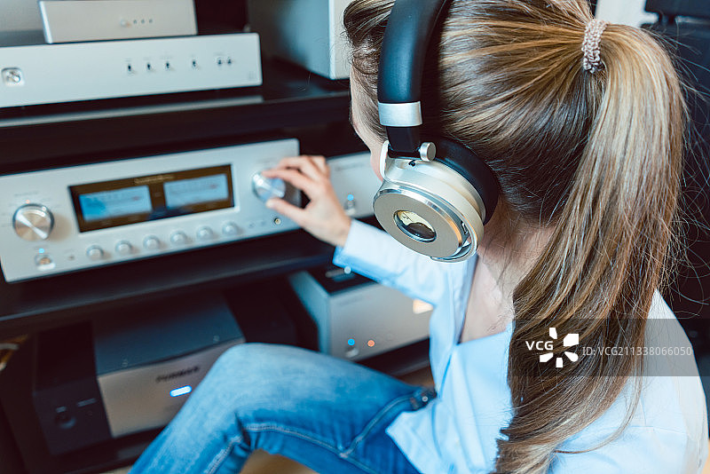 女人戴着耳机在家里通过高保真音响听音乐图片素材