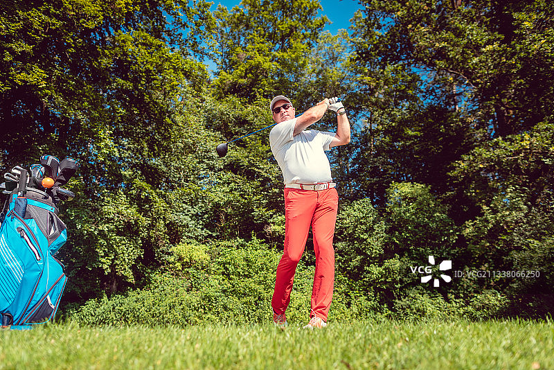 高尔夫球选手在发球台将球击得很远，远击图片素材