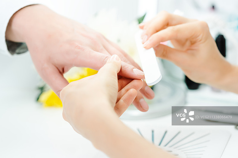 一个女人在美甲店里给一个男人锉指甲图片素材