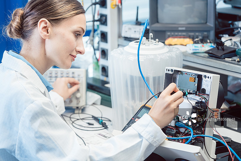 女工程师在实验室的测试台上测量电子产品的EMC符合性图片素材