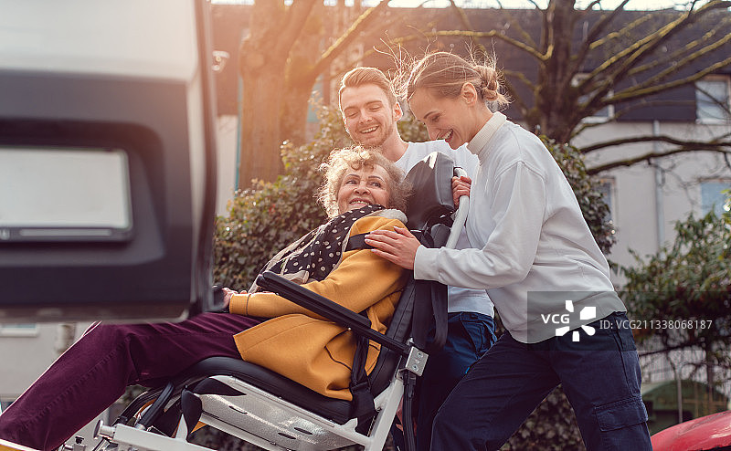 两名助手将残疾的老妇人送上轮椅图片素材