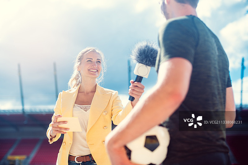 记者手拿麦克风在体育场采访足球运动员图片素材