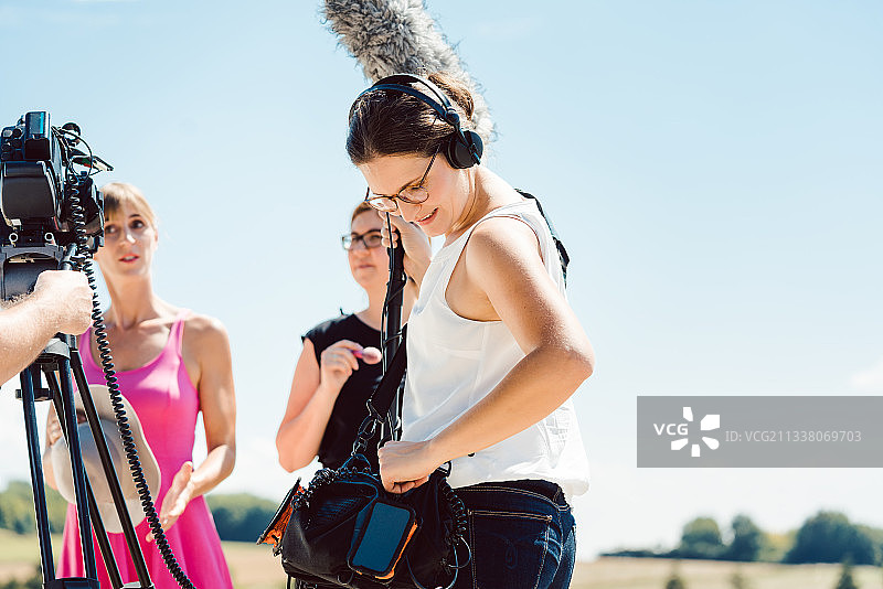 录音师在视频制作现场用麦克风操作她的设备图片素材