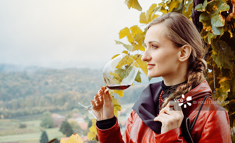 站在葡萄藤前的葡萄酒厂里品酒的女人图片素材