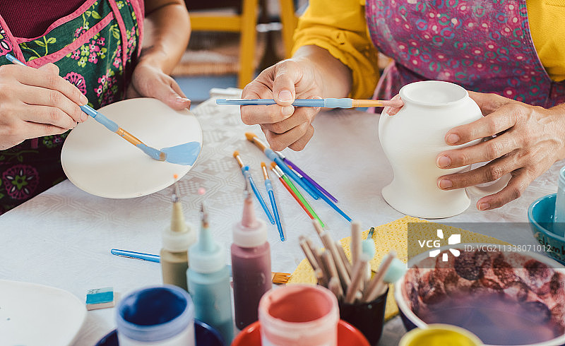 妇女用画笔给手工盘子上色图片素材
