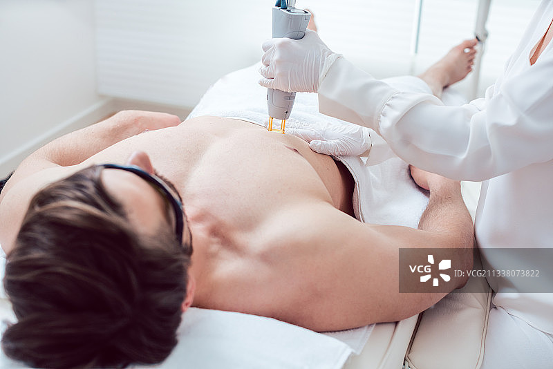 美容师使用现代激光设备去除男人的胸毛图片素材