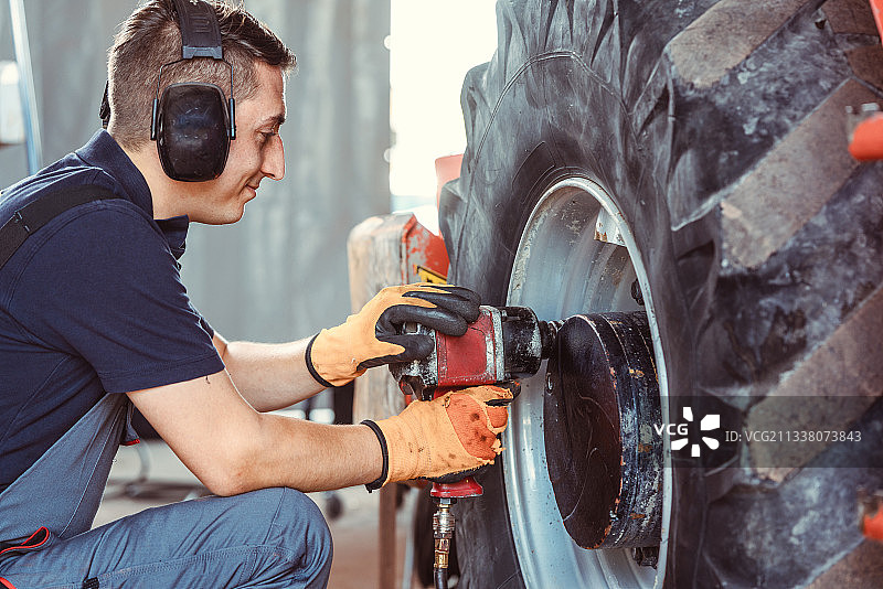 农机机修工用电动工具在车轮上工作图片素材