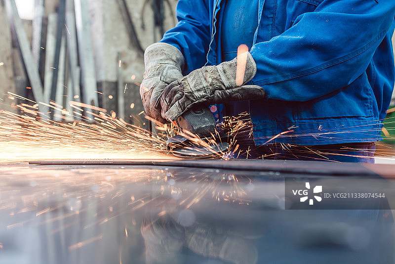 金属厂工人用圆盘磨床磨削工件，火花飞溅图片素材