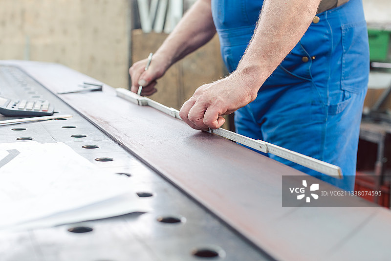 金属工人用折尺测量钢带以备切割图片素材