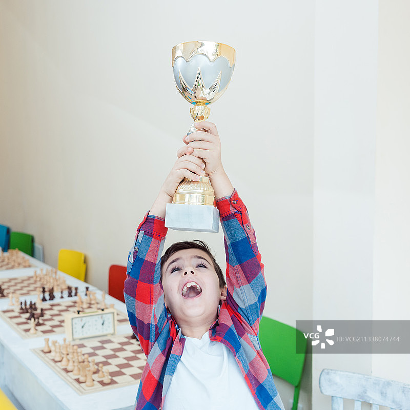 男孩兴奋地展示他在国际象棋比赛中赢得的奖杯图片素材