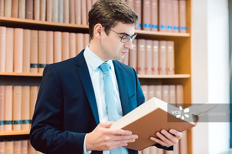 律师在他的办公室里阅读厚厚的判例书思考一个案件图片素材