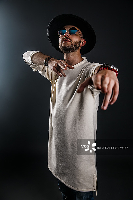 戴帽子的年轻男人站在黑色背景前图片素材