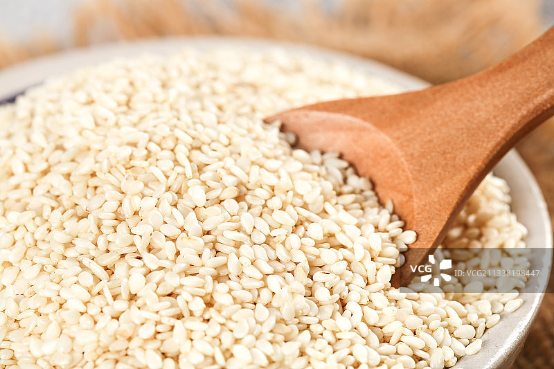 一碗脱皮白芝麻和勺子上挖着芝麻图片素材