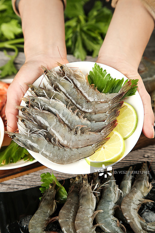 手上端着一盘对虾图片素材