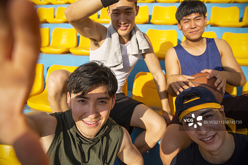 四个青年男子打篮球坐在学校看台休息自拍图片素材