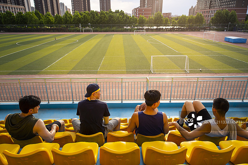 四个青年男子打篮球后坐在学校看台休息放松图片素材