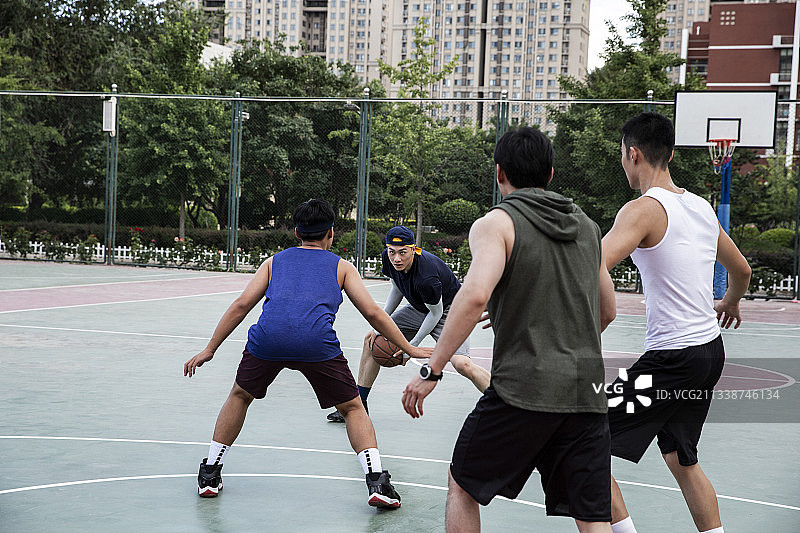 四个青年男子在学校篮球场打篮球比赛图片素材