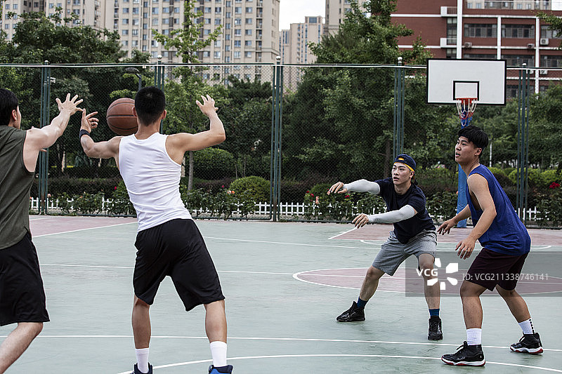 四个青年男子在学校篮球场打篮球比赛图片素材