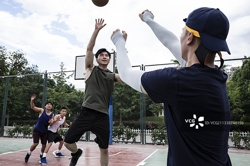 四个青年男子在学校篮球场打篮球比赛图片素材