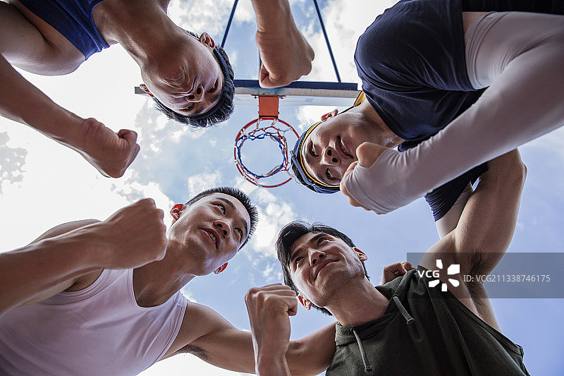 四个打篮球青年男子在学校篮球场团结一起加油图片素材