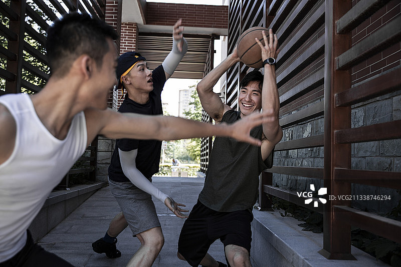 三个青年男子在学校走廊嬉戏练习篮球图片素材