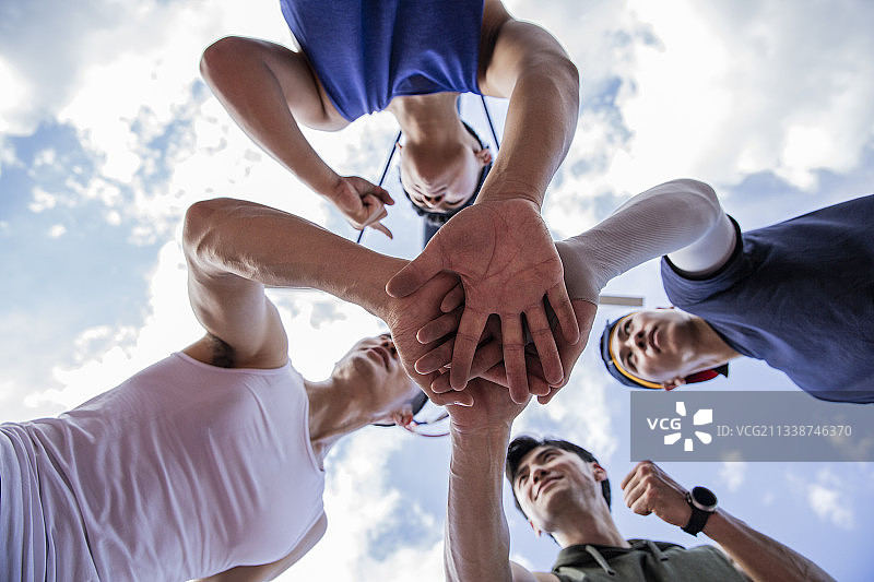 四个打篮球青年男子在学校篮球场团结一起加油图片素材