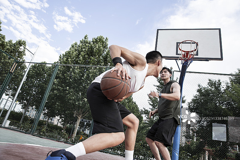 两个青年男子在学校篮球场打篮球比赛图片素材