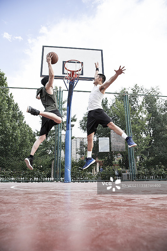 两个青年男子在学校篮球场打篮球灌篮图片素材