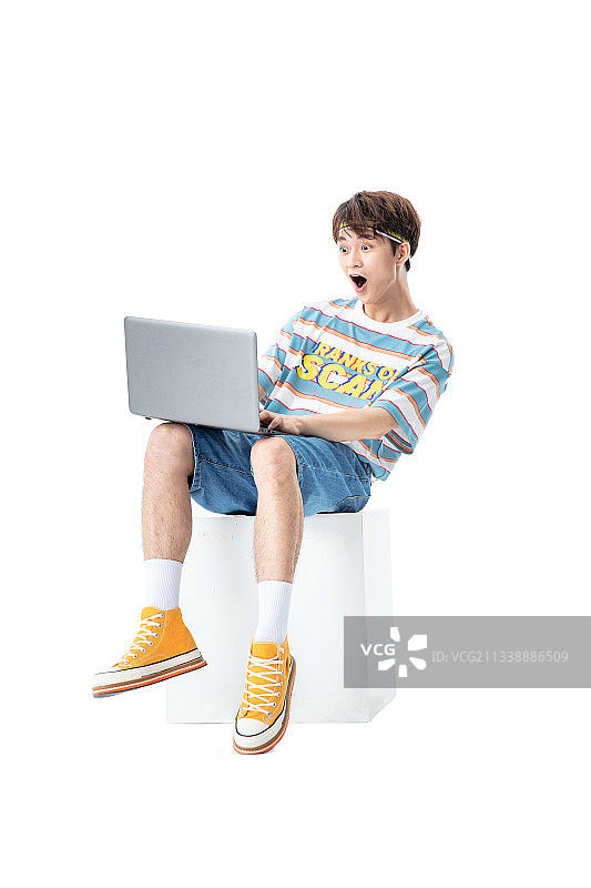 坐在木箱子上使用电脑的年轻男生图片素材