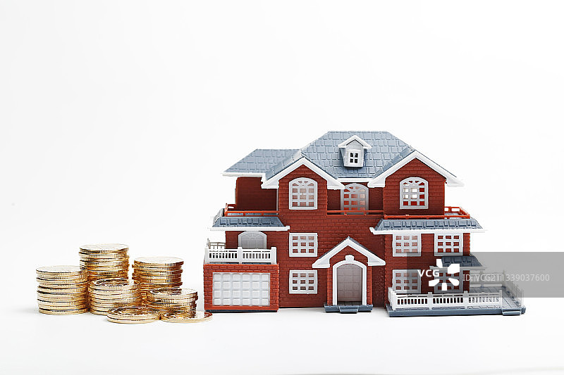 硬币堆放在房屋模型前图片素材
