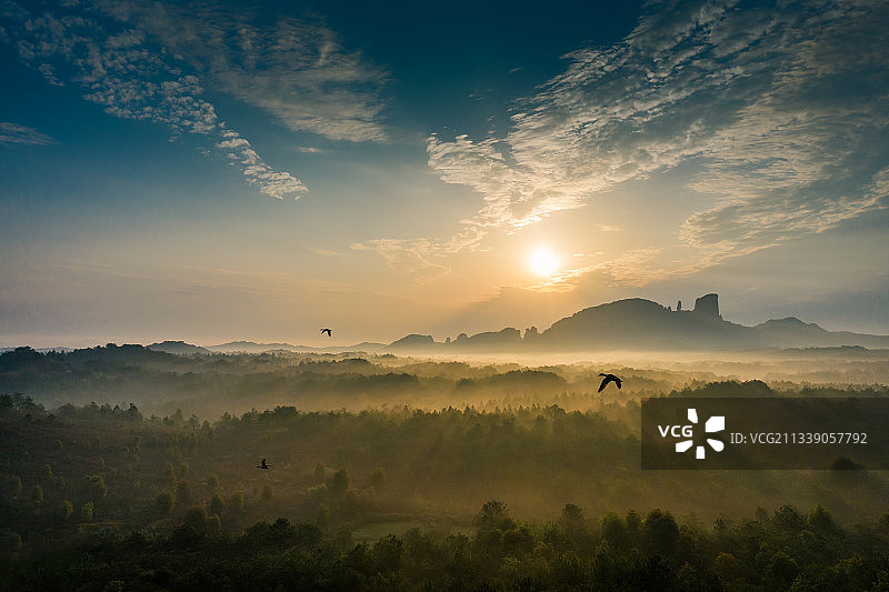 晨光穿过龟峰周边树林间的晨雾形成漂亮的光束图片素材