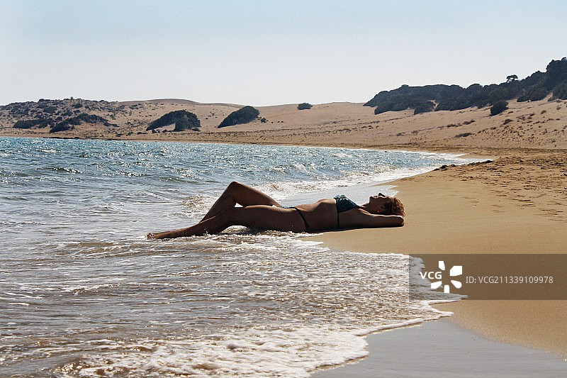 躺在海滩岸边的女人，以天空为背景图片素材