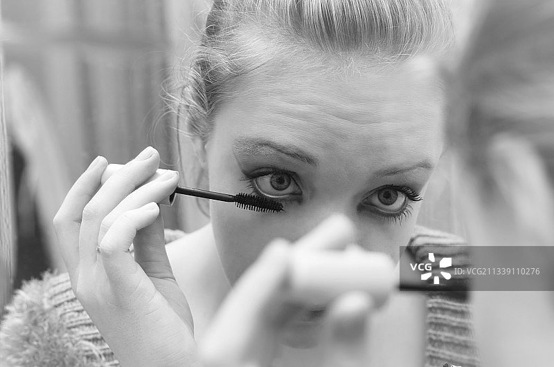 女人在镜子前涂抹彩色妆容特写图片素材