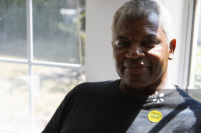 微笑的年长男人贴着“我接种了COVID-19疫苗”的贴纸图片素材