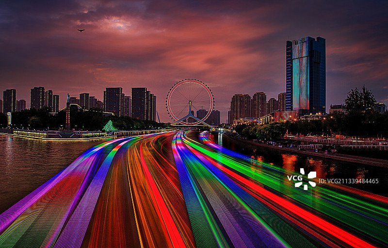天津之眼，傍晚繁忙豪华游船的光轨犹如七彩之虹铺满海河图片素材