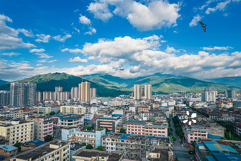 蓝天白云下有鸟飞翔的远山和县城，舶拍广西南宁市上林县图片素材