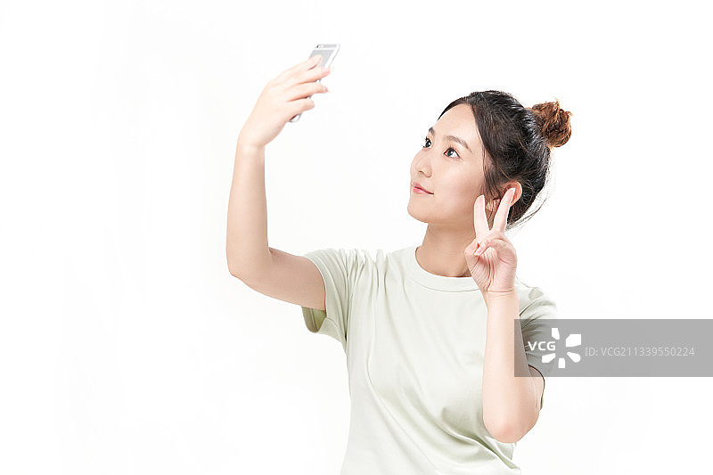 白色背景前正在玩手机的漂亮女生图片素材