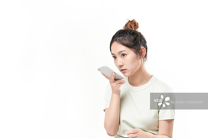 白色背景前正在玩手机的漂亮女生图片素材