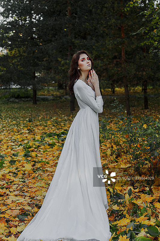 年轻女子秋季站在田野上侧视图图片素材