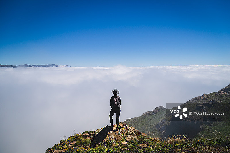 站在山上的年轻男人，背景是天空图片素材