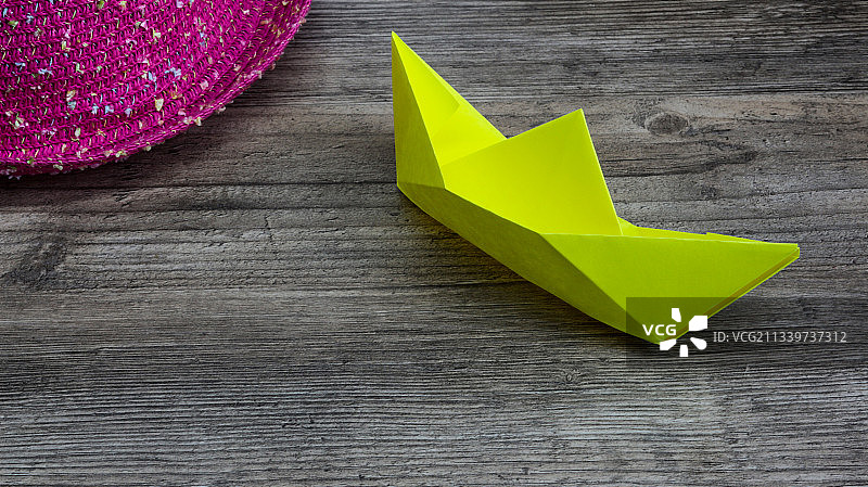 折纸，木桌上的黄色纸船和粉色帽子图片素材