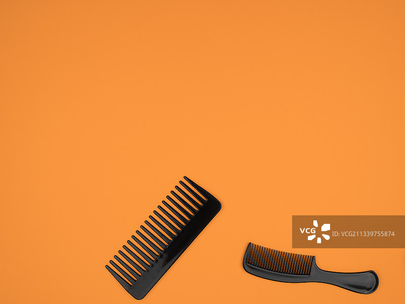 橙色背景上的两把塑料梳子图片素材