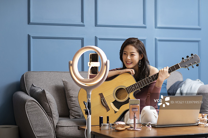 年轻女子在家直播弹奏吉他图片素材
