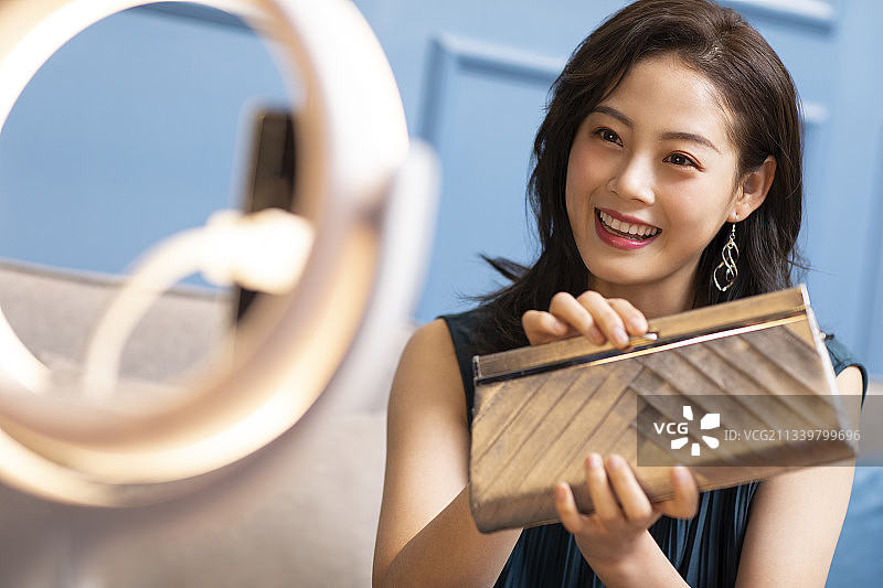 年轻女子在家直播卖时尚女包图片素材