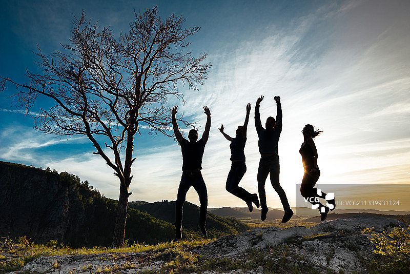 日落时分朋友们在山上跳跃的剪影图片素材