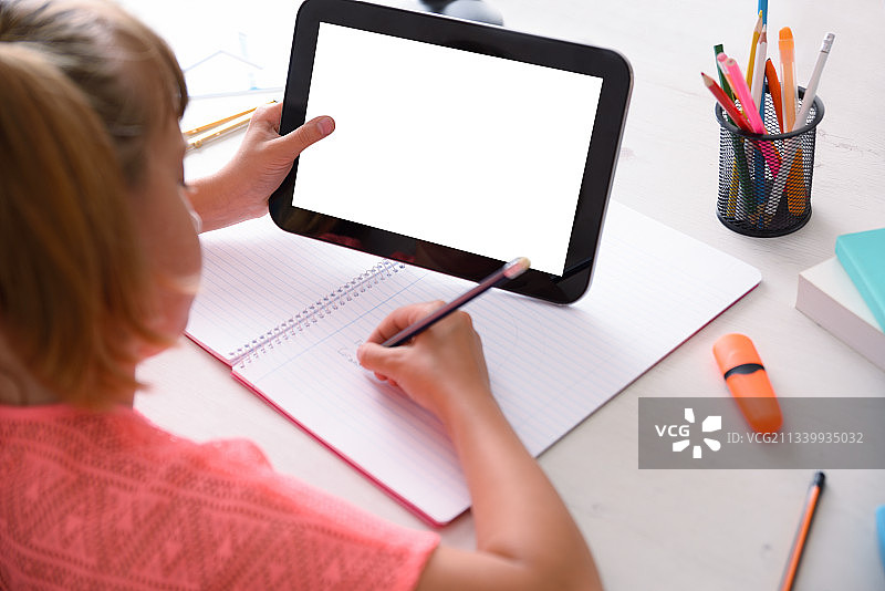 女孩在桌子上使用平板电脑（高角度拍摄）图片素材
