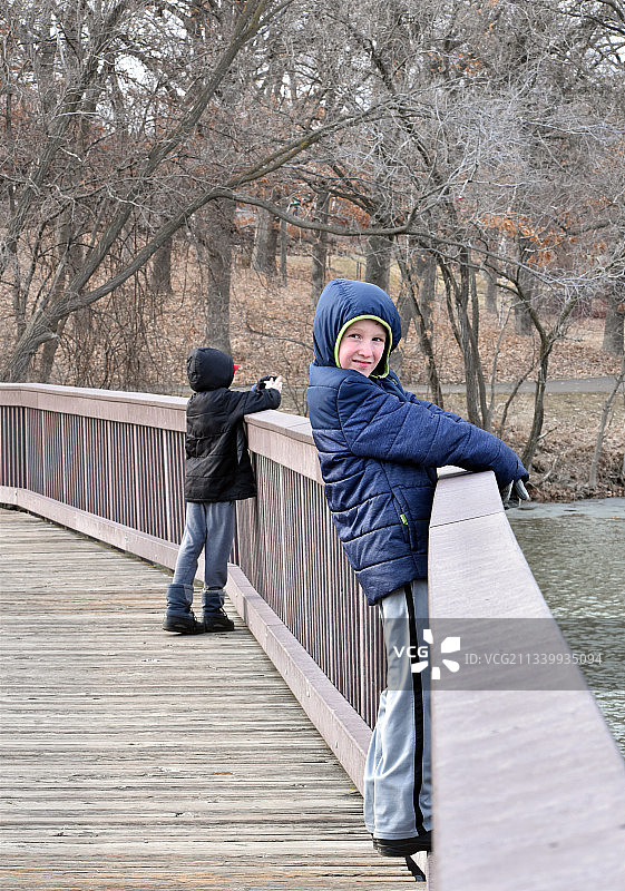 母亲和儿子站在人行天桥上的侧面照图片素材